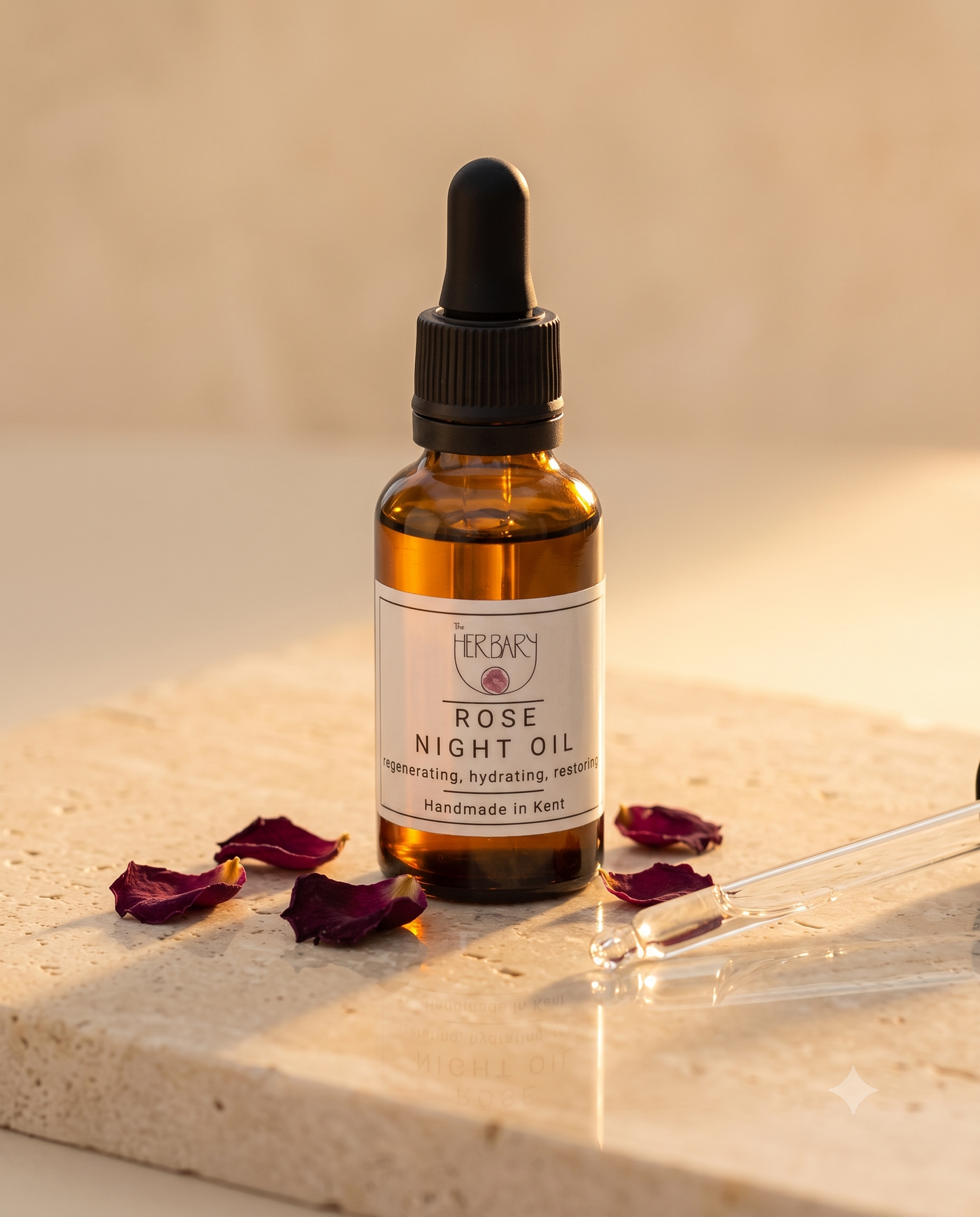 The Herbary Rose Night Oil bottle with dropper and rose petals