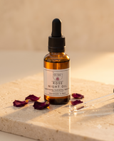 The Herbary Rose Night Oil bottle with dropper and rose petals