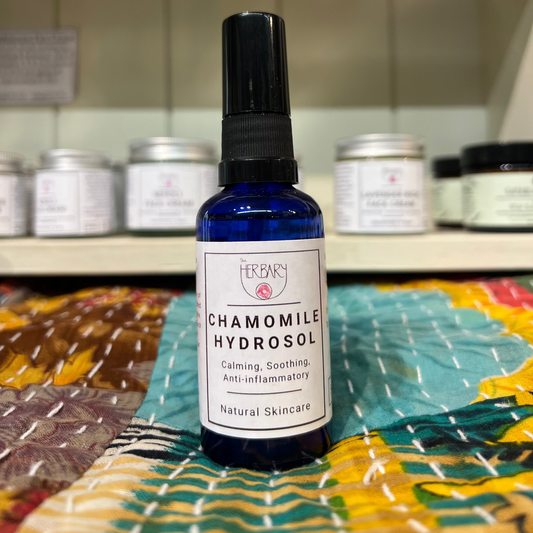 Bottle of chamomile hydrosol on a colorful surface with shelves in the background