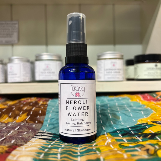 Bottle of Neroli Hydrosol on a colorful fabric background with shelves in the background