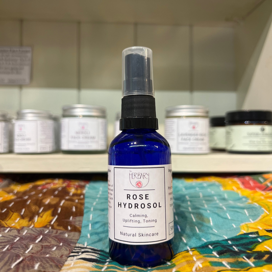 Bottle of Rose Hydrosol on a colorful fabric with shelves in the background