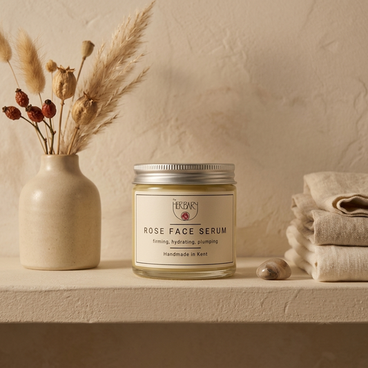 The Herbary Rose Face Serum jar beside dried botanicals and folded linen